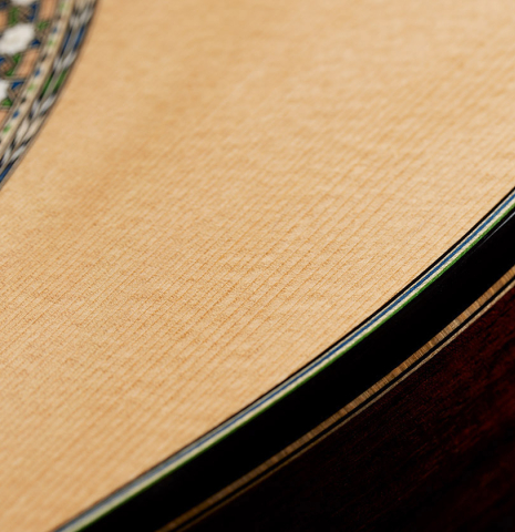 The top binding and purflings of a 2024 Miguel Angel Gutierrez classical guitar made of spruce and Indian rosewood.