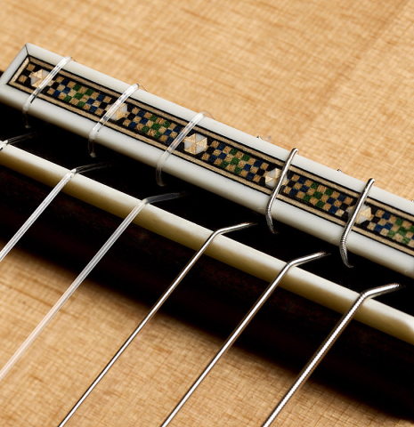 The bridge, tie-block and saddle of a 2026 Miguel Angel Gutiérrez classical guitar made of spruce and Indian rosewood
