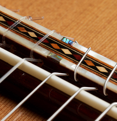 The bridge, tie-block and saddle of a 2025 Miguel Angel Gutierrez "REG 2025" classical guitar made of cedar and padauk