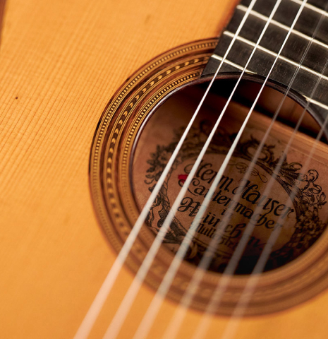 This is a closeup of the rosette and label of a 1927 Hermann Hauser I classical guitar made with spruce for the soundboard and maple for the back and sides.