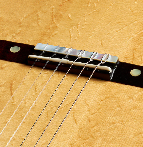 The bridge, tie-block and saddle of a 2013 Hermann Hauser III "Llobet" classical guitar made of spruce and CSA rosewood