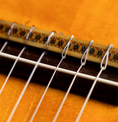 The bridge and saddle of a 1965 Hernandez y Aguado classical guitar made with spruce and Indian rosewood