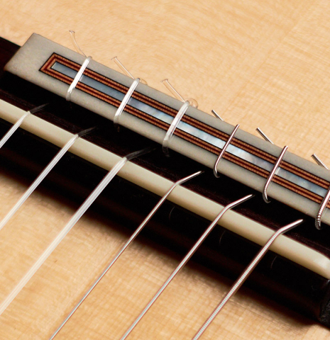 The bridge and saddle of a 2022 Dietmar Heubner classical guitar made with spruce and African rosewood