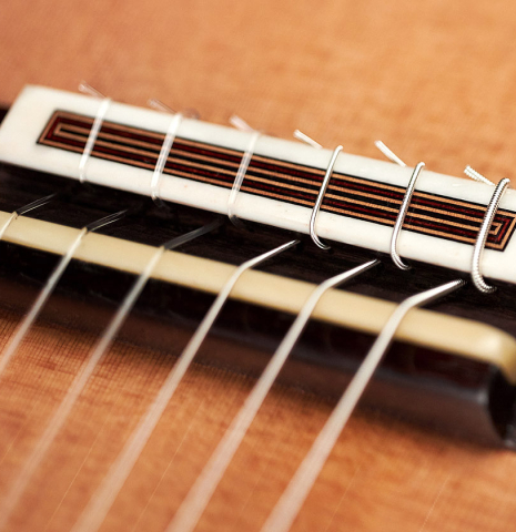 The bridge and saddle of a 2022 Dietmar Heubner classical guitar made with cedar and African rosewood