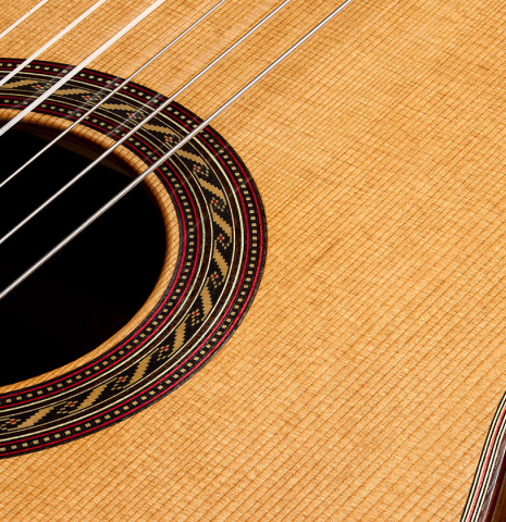 The soundboard and rosette of a 2025 Kenny Hill "New Century CD/SP" classical guitar made of a cedar/spruce double-top and Indian rosewood back and sides
