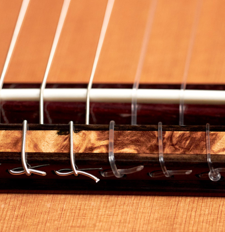The ornamented bridge and saddle of a 2022 Kenny Hill “Signature Legacy 640 CD/SP” CD/IN classical guitar