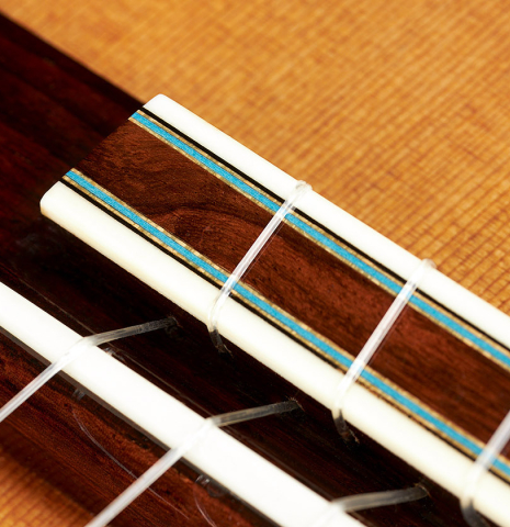 The bridge, tie-block and saddle of a 2020 Kenny Hill "Heritage" classical guitar made of cedar and Indian rosewood