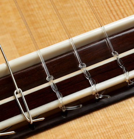 The bridge, tie-block and saddle of a 2008 Kenny Hill "1937 Hauser" classical guitar made of spruce and Indian rosewood