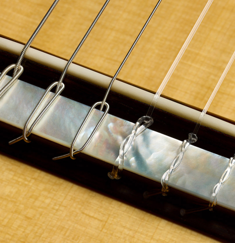 The bridge, tie-block and saddle with mother-of-pearl inlay of a 2009 Kenny Hill "Torres 640 Lattice Double Top" classical guitar made of spruce and maple
