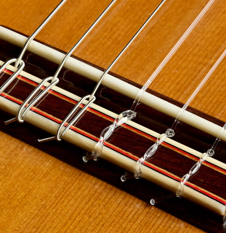 The bridge, tie-block and saddle of a 2010 Kenny Hill "Signature CD/SP" classical guitar with electronics made of cedar/spruce and Indian rosewood