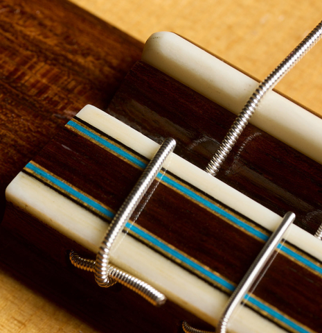 The bridge, tie-block and saddle of a 2020 Kenny Hill "Heritage" classical guitar made of spruce and Indian rosewood