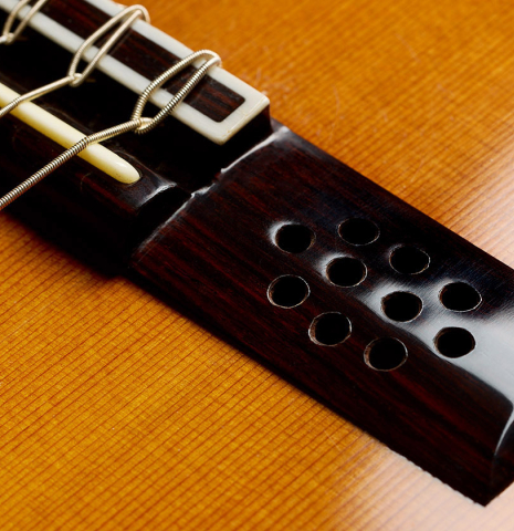 The mini sound-holes in the bridge of a 2009 Dieter Hopf “Super Classic” classical guitar made of cedar and Indian rosewood