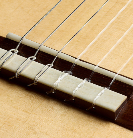The bridge, tie-block and saddle of a 2025 Brian Itzkin classical guitar made of spruce and Indian rosewood