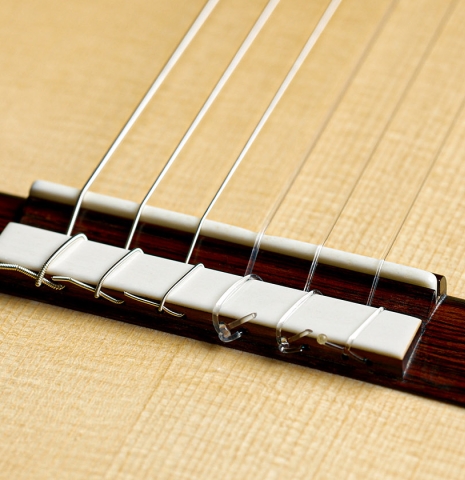 The bridge, tie-block and saddle of a 2026 Brian Itzkin classical guitar made of spruce and African rosewood