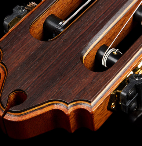 The carved headstock shape of a 2002 Paul Jacobson classical guitar made of cedar and Indian rosewood