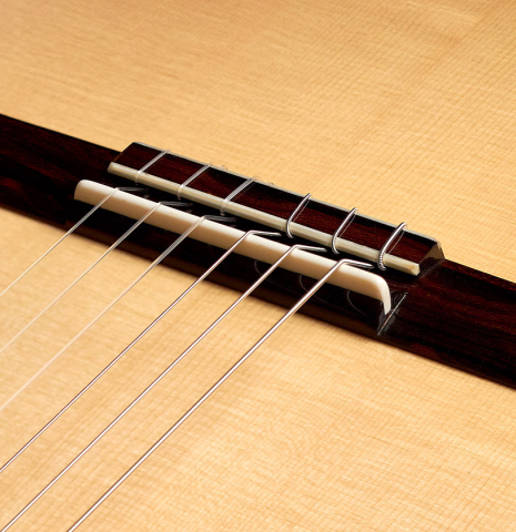 The bridge and saddle of a 2022 Wolfgang Jellinghaus "Signature SP/SP" double top classical guitar made of spruce and ziricote