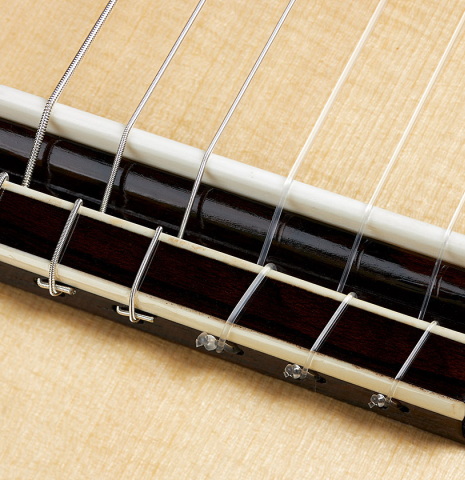 The bridge, tie-block and saddle of a 2024 Wolfgang Jellinghaus "Signature SP/SP" double top classical guitar made of spruce and ziricote