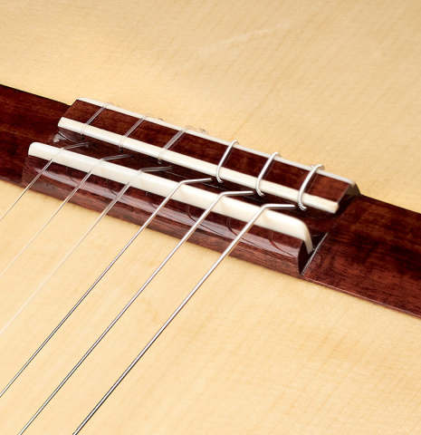 The bridge and saddle of a Wolfgang Jellinghaus "1912 Ex-Segovia" classical guitar made of spruce and Pau Ferro.