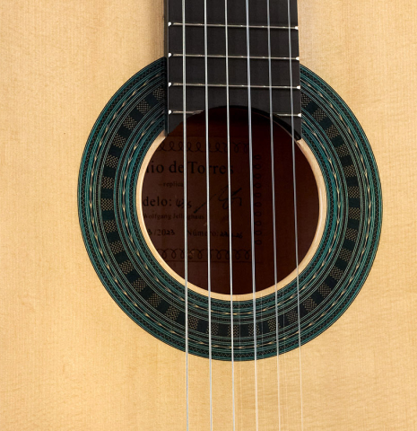 The soundboard and rosette of a Wolfgang Jellinghaus “Torres 43 - clear” classical guitar made with spruce and maple.