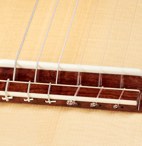 The bridge and saddle of a 2023 Wolfgang Jellinghaus "1912 Ex-Segovia 640" classical guitar made of spruce and granadillo.