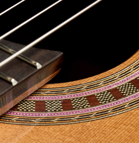 The elevated fingerboard and rosette of a Wolfgang Jellinghaus "Signature CD/SP 640" classical guitar made of cedar and Granadillo