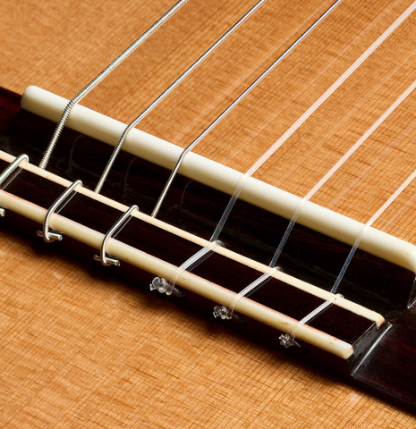 The bridge, tie-block and saddle of a 2025 Wolfgang Jellinghaus "Signature CD/SP" classical guitar made of cedar/spruce and ziricote