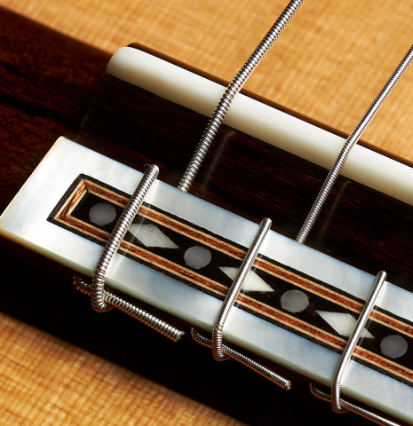The bridge, tie-block and saddle of a 2023 Francisco Jimenez classical guitar made of cedar and Indian rosewood