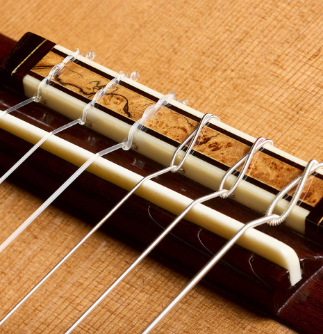 The bridge, tie-block and saddle of a 2026 So Kimishima “Luna” classical guitar made of cedar and African rosewood