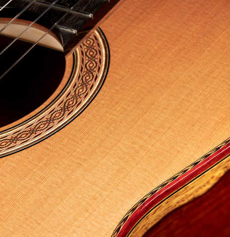 Closeup of the top, sides, rosette, purflings and bindings of a 2023 Zoran Kuvac classical guitar made of cedar and cocobolo.