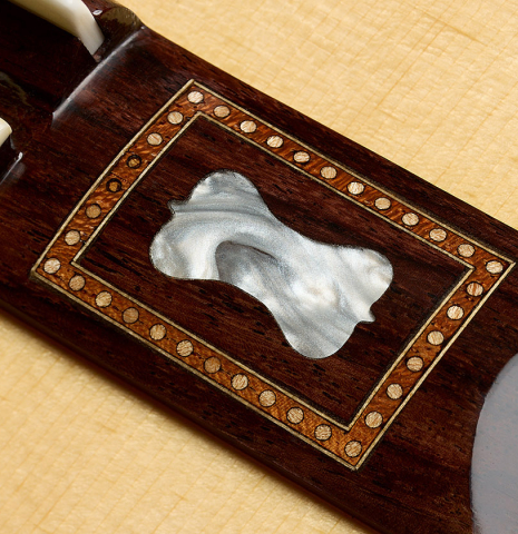 The mother-of-pearl inlay in the wings of the bridge of a La Cañada "Model 17" classical guitar made of spruce and maple