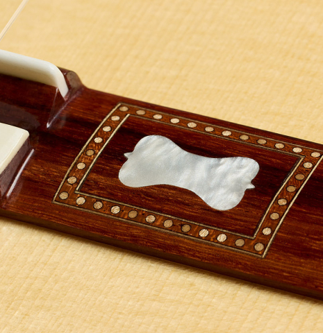 The mother-of-pearl inlay in the wing of the bridge of a La Cañada "Model 17" classical guitar made of spruce and Granadillo