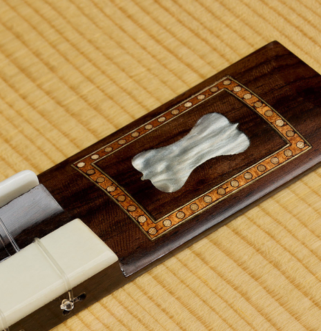The mother-of-pearl inlay in the wings of the bridge of a La Cañada "Model 17" classical guitar made of spruce and cypress