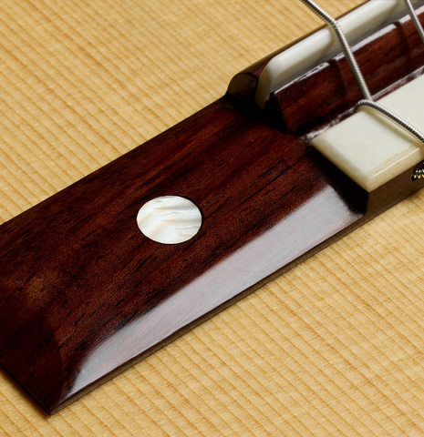 The bridge with mother-of-pearl inlay of a La Cañada "Model 115" classical guitar made of spruce and cypress