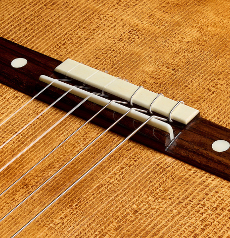 The bridge, tie-block and saddle with mother-of-pearl inlays of a La Cañada "Model 115A" classical guitar made of spruce and cypress