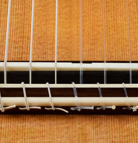 The bridge, tie-block and saddle of a 2025 Paula Lazzarini classical guitar made of cedar and Indian rosewood