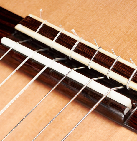 The bridge, tie-block and saddle of a 2023 Paula Lazzarini classical guitar made of cedar and ziricote