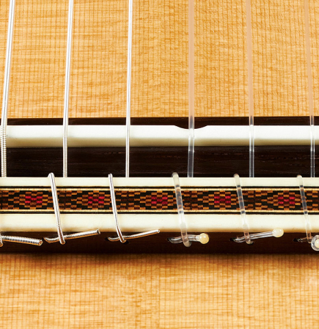 The bridge, tie-block and saddle of a 2023 Paula Lazzarini classical guitar made of cedar and cocobolo