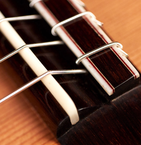 The bridge and saddle of a 2022 Francois Leonard classical guitar made of cedar and African rosewood