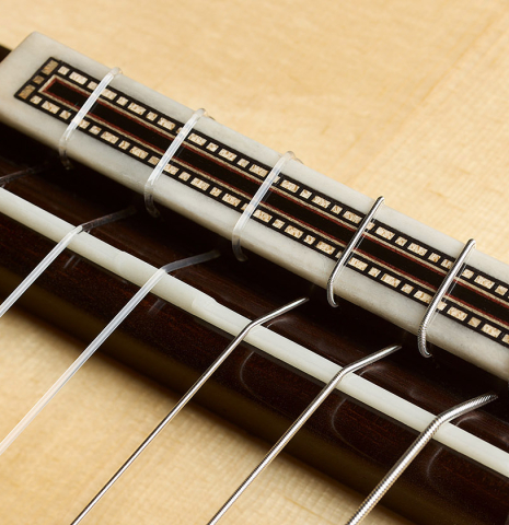 The bridge, tie-block and saddle of a 2026 Valerio Licari "Lesna - REG Special Edition" classical guitar made of spruce and Indian rosewood