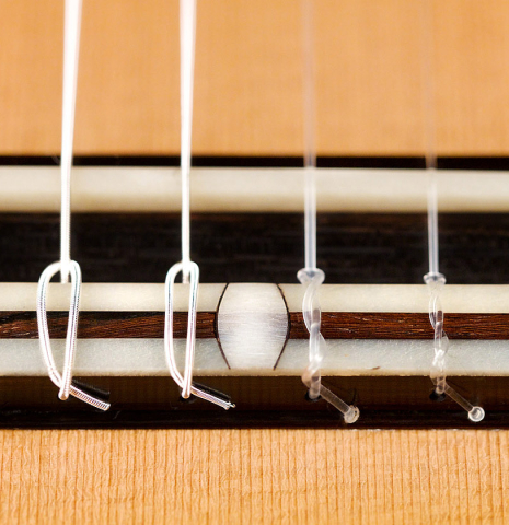 The bridge, tie-block and saddle of a 2021 Bertrand Ligier classical guitar made of cedar and Indian rosewood