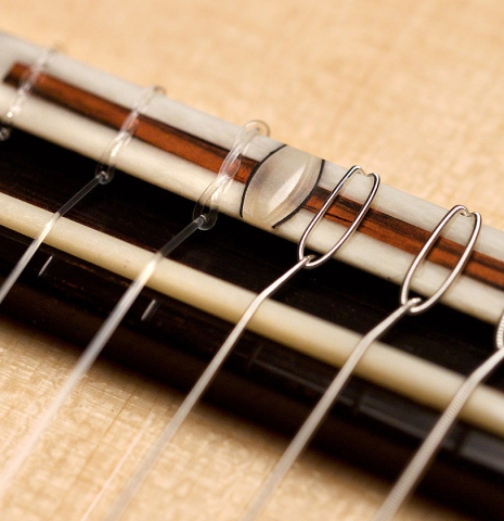A close-up of the bridge and saddle of a 2021 Bertrand Ligier classical guitar made of spruce and African rosewood
