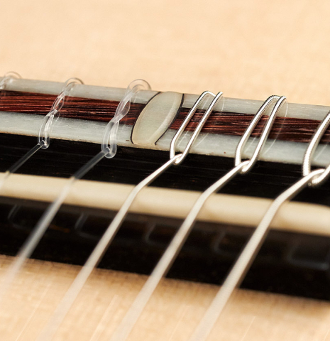A close-up of the bridge and saddle of a 2023 Bertrand Ligier classical guitar made of spruce and African rosewood
