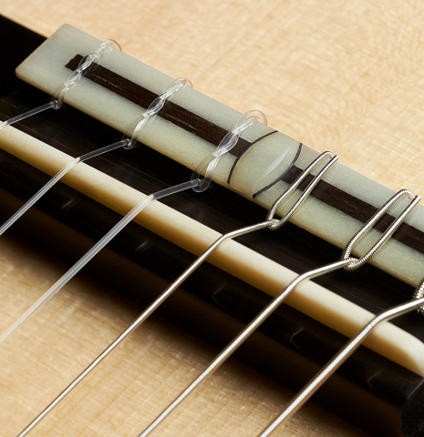 A close-up of the bridge and saddle of a 2023 Bertrand Ligier classical guitar made of spruce and African rosewood