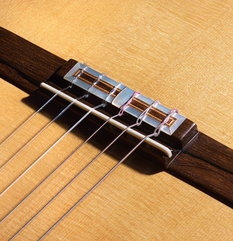 The bridge and saddle of a 2006 Luigi Locatto classical guitar made of spruce and Indian rosewood