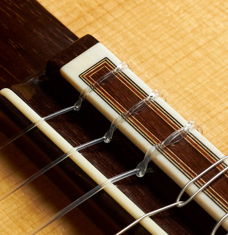 The bridge, tie-block and saddle of a 2019 Luigi Locatto classical guitar made of spruce and Indian rosewood