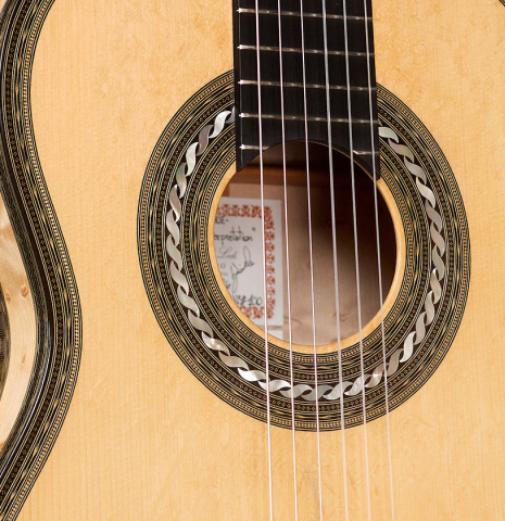 The soundboard and rosette of a 2021 Gabriele Lodi &quot;Torres&quot; classical guitar made of spruce and maple.