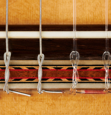 The bridge, tie-block and saddle of a 2012 Marcelino Lopez "1851 Jose Pernas" classical guitar made of spruce and Indian rosewood