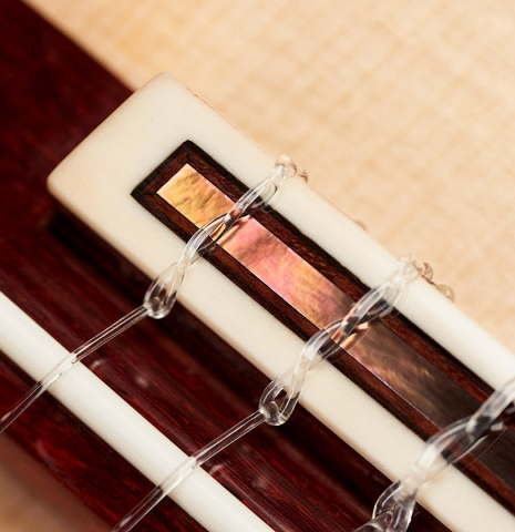 The bridge, tie block and saddle of a 2023 Lucas Martin #100 classical guitar made with spruce top and maple back and sides.