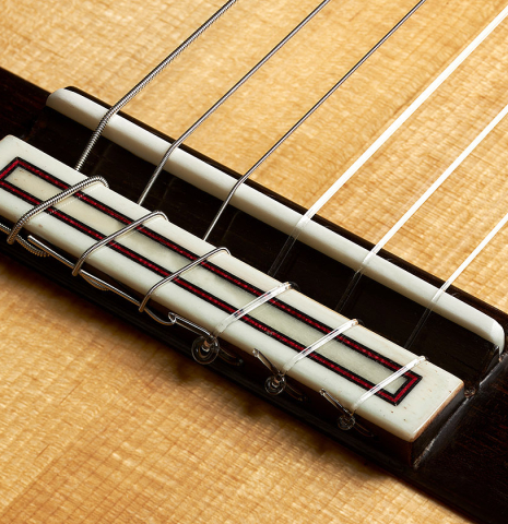 The bridge, tie-block and saddle of a 2023 Fernando Moreno classical guitar made of spruce and Indian rosewood