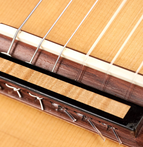 The bridge, 18-hole tie-block and saddle of a 2011 Rafael Moreno Rodriguez classical guitar made of spruce and maple